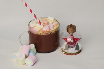 Cocoa with colorful marshmallows and New Year's decorations on a white background — a cozy winter...