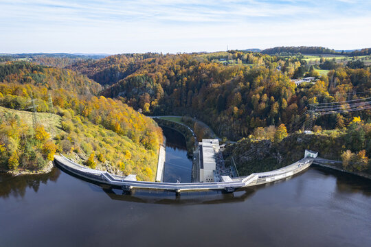 Aerial view of the Ottenstein Dam curving gracefully across the dark waters of the Ottensteiner Stausee, embraced by forests ablaze with autumn colors, Ottenstein, Nieder&Atilde;&para;sterreich, Austria.