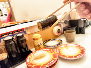 Enjoying freshly prepared sushi rolls at a sushi bar in Japan during lunch hour with vibrant plates