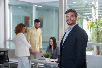 Fototapeta premium Portrait of confident businessman with coworkers collaborating in modern office