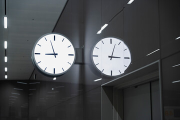 Twin clocks showing different times, mounted on a sleek, modern wall, create a sense of time zones.