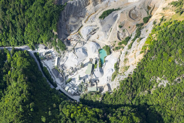 Aerial view of a quarry with contrasting textures of raw stone and lush green forests surrounding, Weizklamm, Steiermark, Austria.
