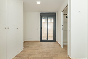 Spacious empty room with integrated white wooden dressing area, top-mounted sliding doors, and an interior LED lighting system