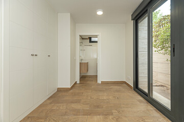Empty contemporary bedroom with white floating wardrobes, indirect downlighting, and longitudinal...