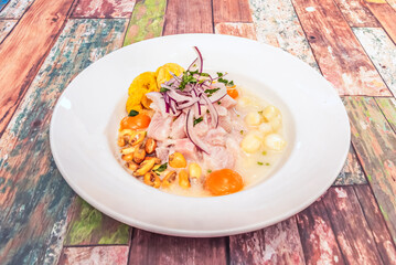 Traditional Peruvian ceviche with thick chunks of fresh white fish, marinated in lime and limo chili, and accompanied by sweet potato, corn, and cancha mountain pepper