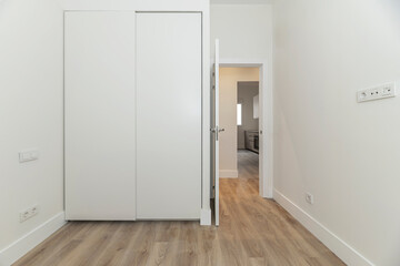 Empty bedroom with a complete white storage solution, including built-in wardrobes, overhead...