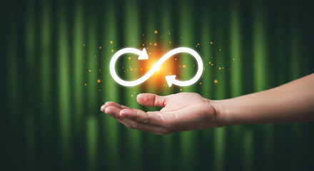 Hand holding glowing infinity loop icon with arrows representing endless cycle, continuity, or renewal