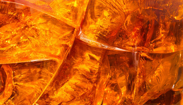 Macro photograph of a texture in golden and amber tones with yellowish sparkles.