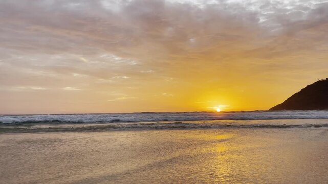 Golden sunset at Nai Harn Beach, Phuket, Thailand, with waves rolling gently to shore under a glowing sky, creating a serene and tropical seascape