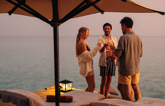 Friends enjoying drinks and cheering at sunset during a beach vacation