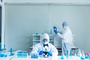 Two asian scientist team reserch chemistry science tube experiment biotech antibody sample in laboratory Cultivate Vaccine against covid-19 virus. Scientist consult, analyze in Chemistry Laboratory