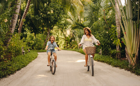 Happy family biking on a lush tropical island during vacation - Powered by Adobe