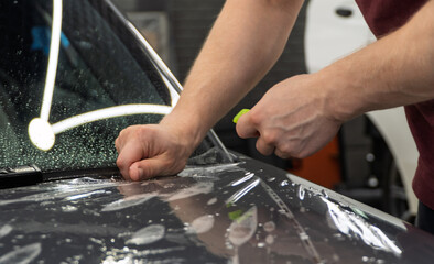 A car wrapping specialist applies a polyurethane film to the car. Detailer smoothes PPF. Car...