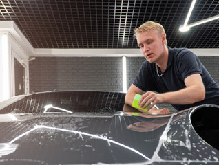 A car wrapping specialist applies a polyurethane film to the car. Detailer smoothes PPF. Car...