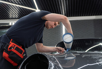 A car wrapping specialist applies a polyurethane film to the car. Detailer smoothes PPF. Car...
