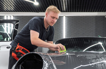 A car wrapping specialist applies a polyurethane film to the car. Detailer smoothes PPF. Car...