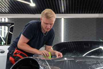 A car wrapping specialist applies a polyurethane film to the car. Detailer smoothes PPF. Car...