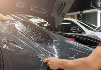 A car wrapping specialist applies a polyurethane film to the car. Detailer smoothes PPF. Car...