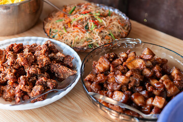 Traditional Indonesian dishes on a wooden table, featuring crispy fried pork, sweet soy braised pork, and stir-fried noodles with vegetables. Delicious homemade Asian cuisine for authentic food cultur