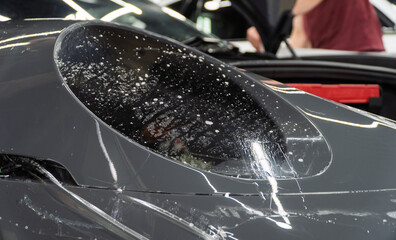 A car wrapping specialist applies a polyurethane film to the car. Detailer smoothes PPF. Car...