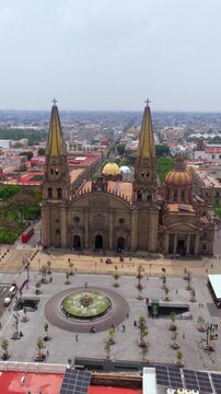 Drone aerial of Guadalajara Cathedral with twin towers, dome, and fountain in main plaza, Jalisco, Mexico. Vertical shot