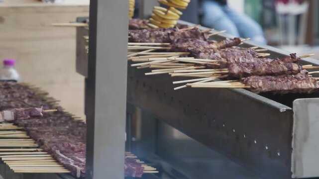 Slow motion: traditional Italian arrosticini lamb skewers grilling over charcoal. Authentic specialty showcases tender meat on wooden sticks with smoky barbecue atmosphere.