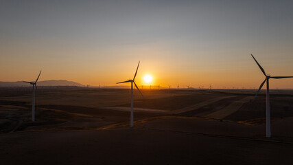 Wind turbines generating sustainable energy during a vibrant sunset in pedrola, zaragoza, Aragon,...