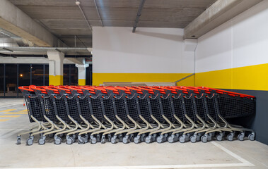 Many shopping carts are neatly arranged in an underground parking garage, ready for customers to use