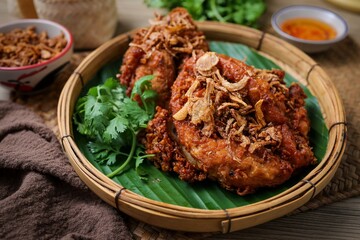 Fried chicken topped fried shallots with sticky rice and thai sauce in banana leaf on wooden background, thai called kai tod hat yai