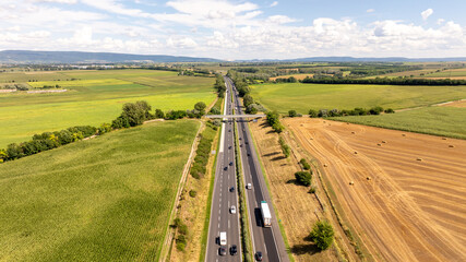 Aerial view of vehicles driving on highway m1 through agricultural landscape in tata, Hungary,...