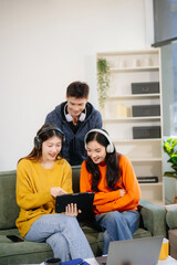 Obraz premium Group of young Asian students working on a project with laptops and tablets. Cozy indoor setting,