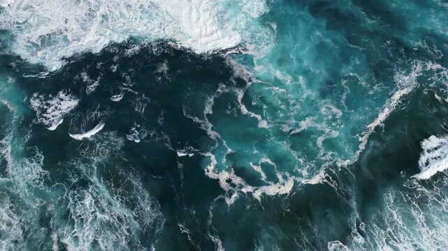 Aerial view of the ocean's surface, where deep blue hues meet frothy white waves creating a dynamic and textured seascape, Porto Formoso, Azores, Portugal.