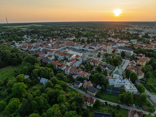 Drone aerial view of the main square in Lezajsk, Poland, with historic buildings, churches and colorful architecture, surrounded by greenery on a sunny summer day.