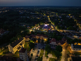 Drone view of Lezajsk City Days celebration with concerts, stage lights, illumination, attractions for children and crowds enjoying music and summer festivities. City days celebration in Poland.
