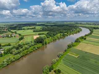 San river in Poland. Aerial drone view of the San River in Lezajsk, Poland, with a bridge crossing over the water. Scenic summer landscape with greenery, flowing river and town surroundings.
