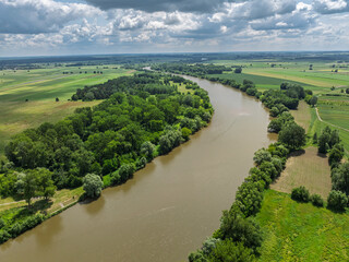 San river in Poland. Aerial drone view of the San River in Lezajsk, Poland, with a bridge crossing over the water. Scenic summer landscape with greenery, flowing river and town surroundings.