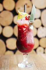 Red tropical cocktail with ice in elegant glass. Garnished with pineapple leaf and umbrella....
