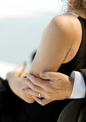 Man gently hugging woman sitting outdoors. Man's hand on woman's arm close-up. Concept of family,...