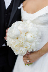 The bride holds a bouquet of white peonies in her hands on her wedding day. Beautiful wedding...