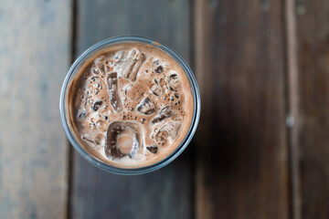 Iced chocolate beverage in plastic glass, top view on wood table.