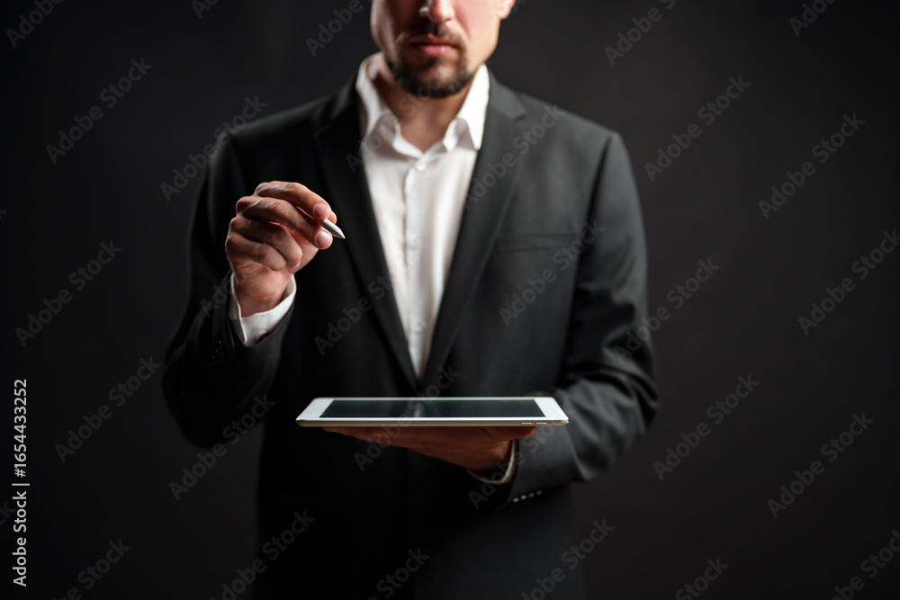 Aufkleber professional man in a suit uses a tablet to take notes in front of a dark background