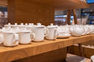 White ceramic teacups and teapots on shelves in shopping mall