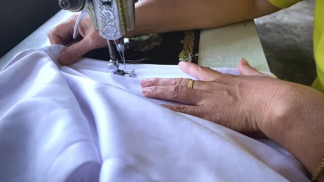 A woman working on the edge of fabric using an overlock sewing machine, close-up.