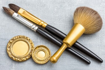 Gold makeup brushes and compacts on a gray surface