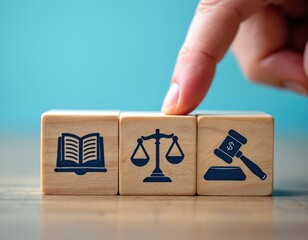 Naklejka na ściany i meble Wooden blocks showcase icons of law, justice, and finance. A finger selects a block, symbolizing choice in legal decisions and fairness. Represents legal system, court, and financial regulations.