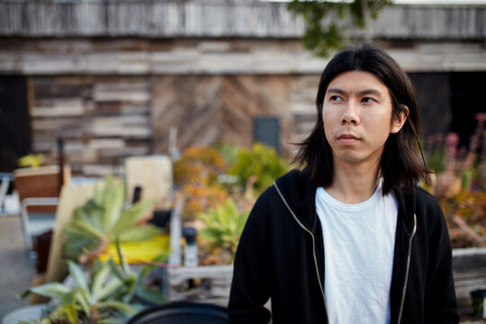 Young Asian man standing outside in warehouse courtyard