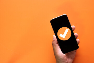 A checkmark icon on a mobile phone screen symbolizing a successful payment or confirmed transaction. A concept for e-commerce, online banking, and fintech apps showing order approval.