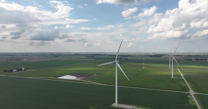 Aerial view of wind turbines standing tall amidst the lush green fields and bright blue skies, creating a striking contrast, Monroeville, Indiana, United States.