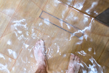 Overhead view of standing water on shower floor due to clogged drain. Tiled surface with visible...