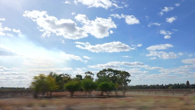Looking out of car window driving by orange fields and agriculture near Griffith, NSW, Australia